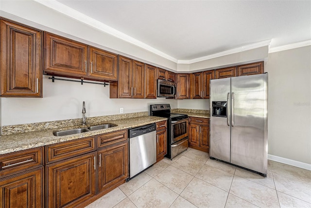 kitchen featuring stainless steel appliances, crown molding, a sink, and light stone counters