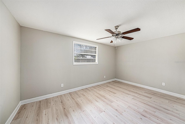 spare room with a textured ceiling, light wood finished floors, a ceiling fan, and baseboards