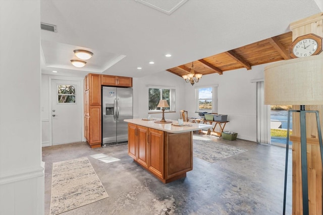 kitchen with stainless steel fridge, concrete flooring, a center island with sink, decorative light fixtures, and wooden ceiling