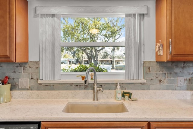 kitchen featuring dishwashing machine, sink, tasteful backsplash, and a healthy amount of sunlight