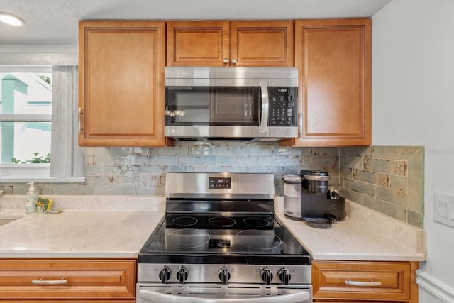 kitchen with stainless steel appliances, tasteful backsplash, and light stone countertops