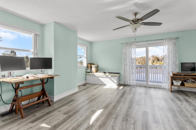 living room featuring ceiling fan, plenty of natural light, and light wood-type flooring