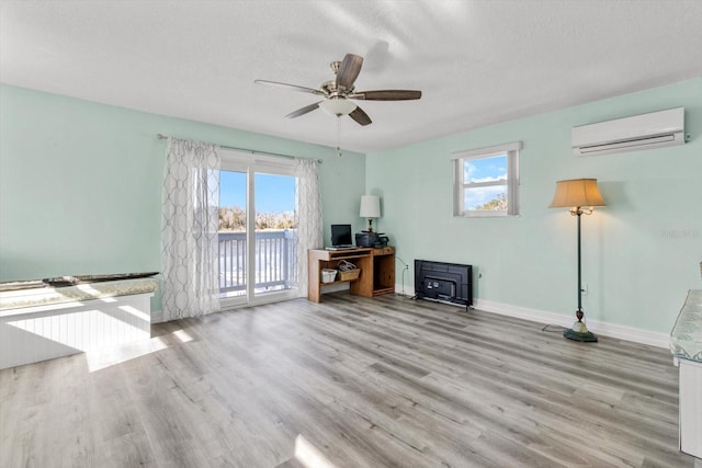 unfurnished living room with a wood stove, an AC wall unit, a textured ceiling, and light wood-type flooring