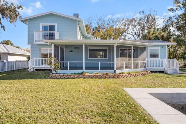 rear view of house featuring a balcony, a sunroom, and a lawn