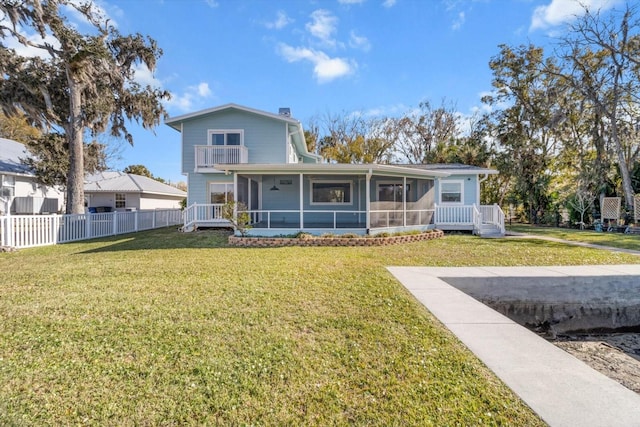 view of front of house featuring a balcony, a front yard, and a sunroom