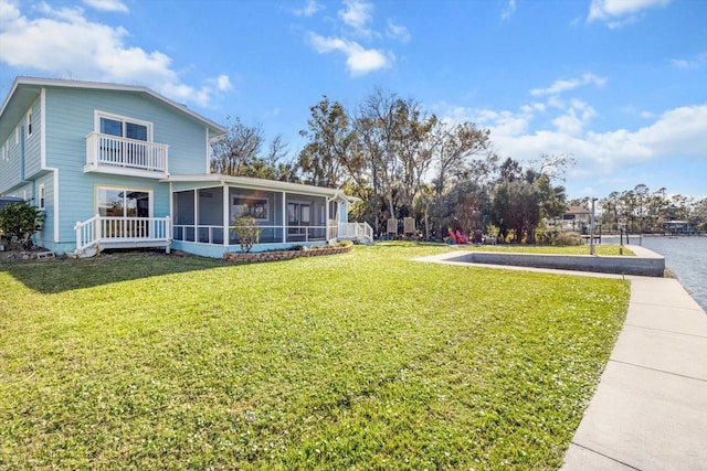 view of yard with a water view, a balcony, and a sunroom