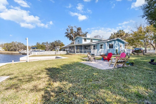 view of yard with a sunroom, a patio, and a water view