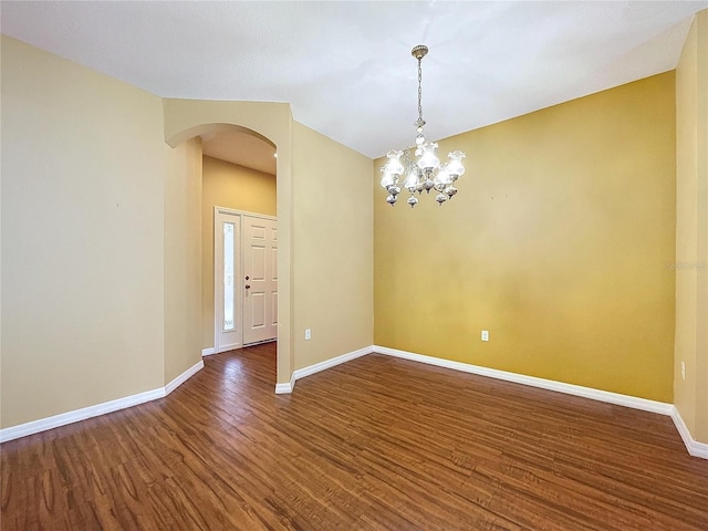 spare room with dark hardwood / wood-style flooring and a notable chandelier