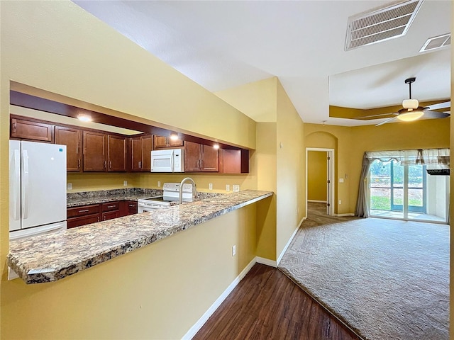 kitchen with light stone counters, white appliances, vaulted ceiling, kitchen peninsula, and ceiling fan