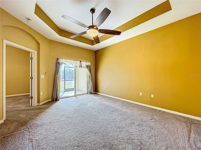 unfurnished room with ceiling fan, a tray ceiling, and carpet