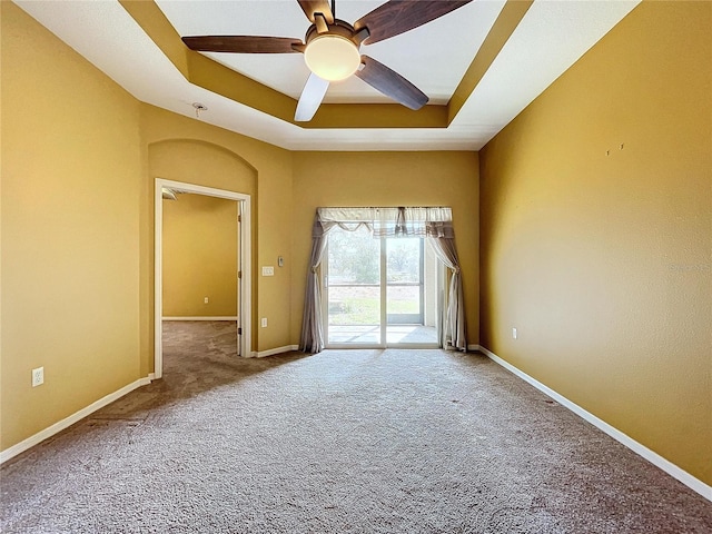 spare room with a raised ceiling, carpet, and ceiling fan