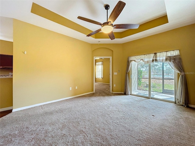 carpeted spare room featuring ceiling fan and a raised ceiling