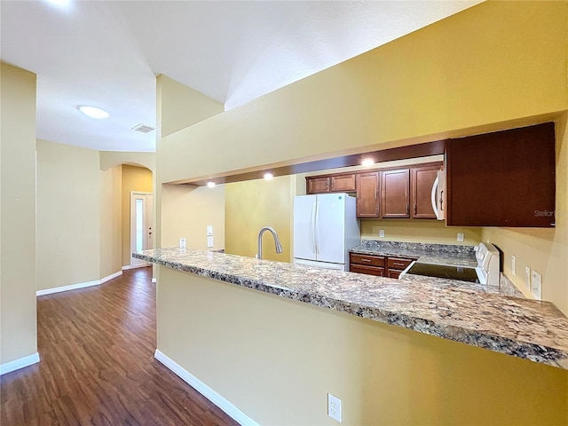 kitchen featuring white appliances, dark wood-type flooring, light stone countertops, and kitchen peninsula