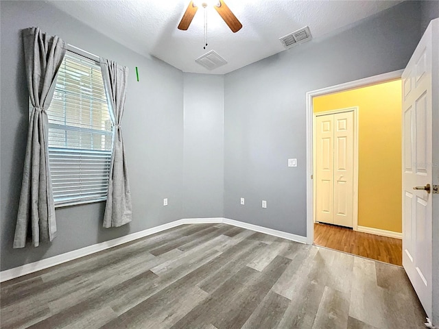 empty room featuring a textured ceiling, wood-type flooring, and ceiling fan