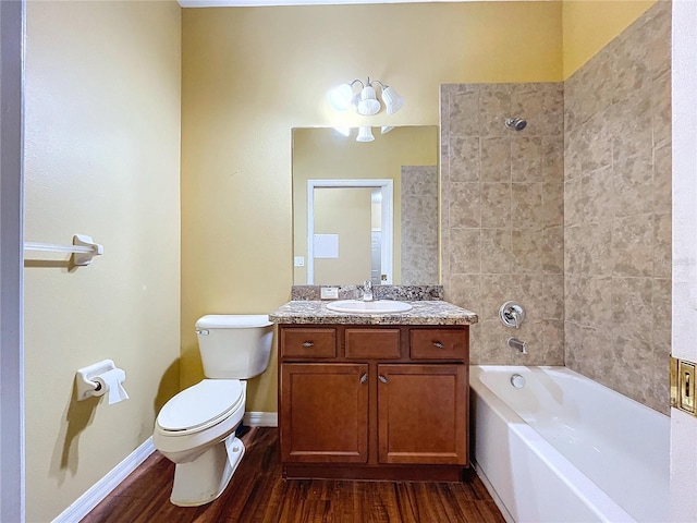 full bathroom featuring wood-type flooring, tiled shower / bath, vanity, and toilet