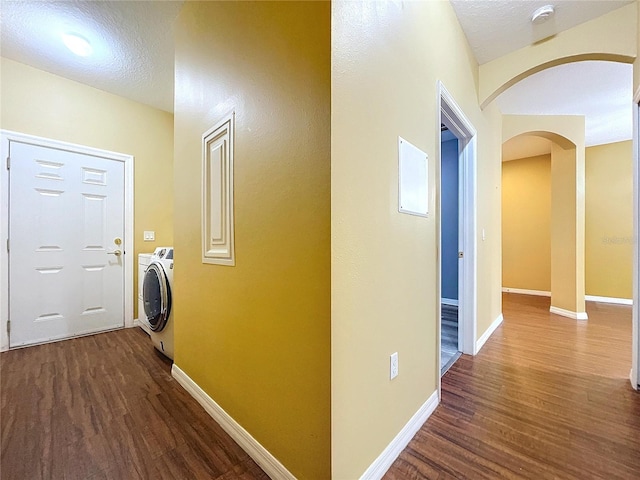 hall with washer / dryer, dark hardwood / wood-style floors, and a textured ceiling