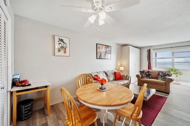 dining area featuring hardwood / wood-style flooring, ceiling fan, and a textured ceiling