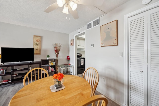 dining space with ceiling fan, wood-type flooring, and a textured ceiling