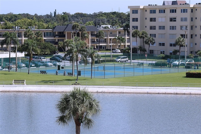 exterior space with a water view, tennis court, and a lawn