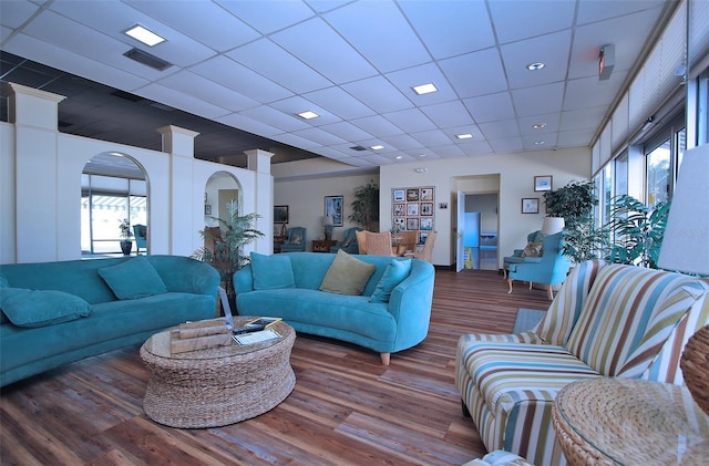 living room featuring a drop ceiling, hardwood / wood-style flooring, and ornate columns