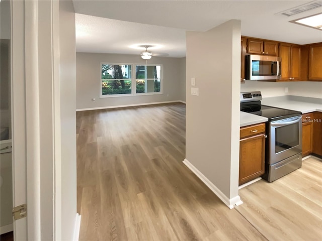 kitchen with brown cabinetry, stainless steel appliances, light countertops, and open floor plan