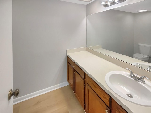 bathroom featuring baseboards, vanity, and toilet