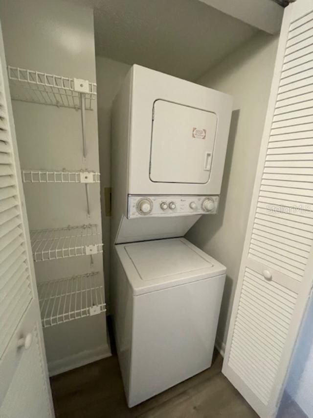 laundry room with laundry area, wood finished floors, and stacked washer / drying machine