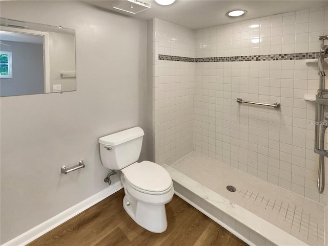 bathroom featuring toilet, a shower stall, baseboards, and wood finished floors