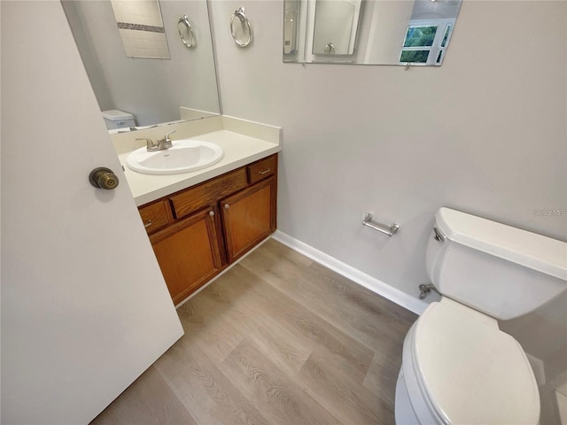 bathroom with toilet, baseboards, wood finished floors, and vanity