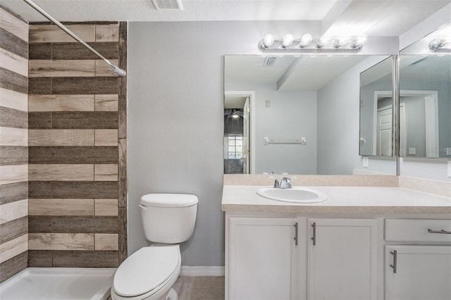 bathroom with vanity, toilet, and a tile shower