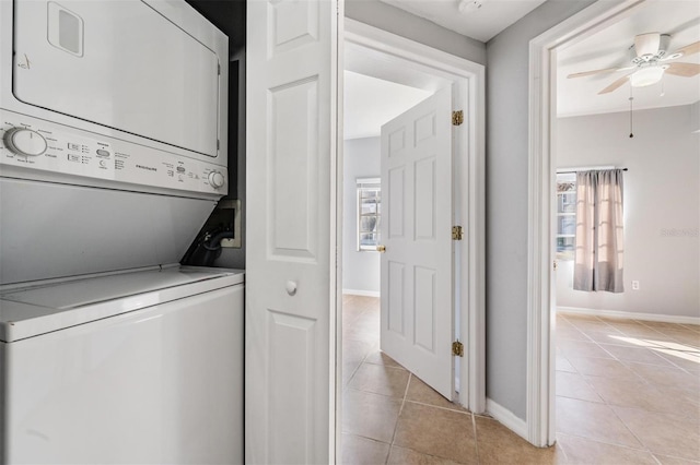 laundry area featuring stacked washer and dryer, light tile patterned flooring, and ceiling fan