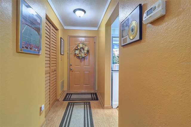 doorway featuring crown molding, light hardwood / wood-style flooring, and a textured ceiling