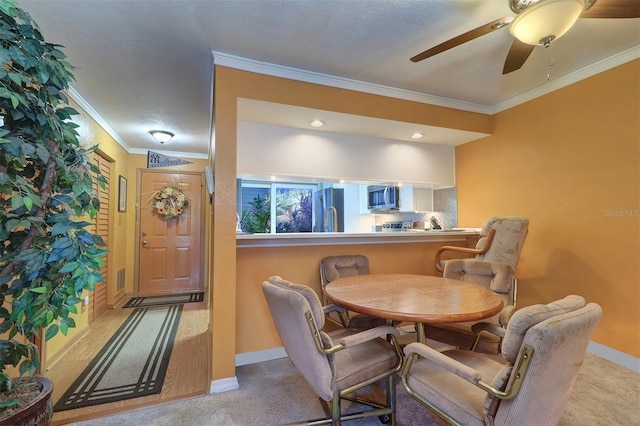 dining room with crown molding, light colored carpet, and ceiling fan