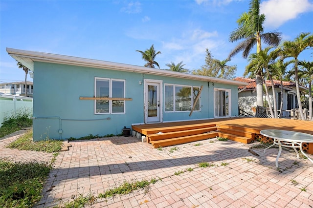 back of property with a deck, a patio, fence, and stucco siding