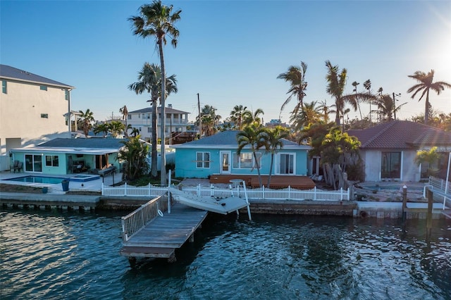 dock area featuring a water view, a residential view, fence, and an outdoor pool