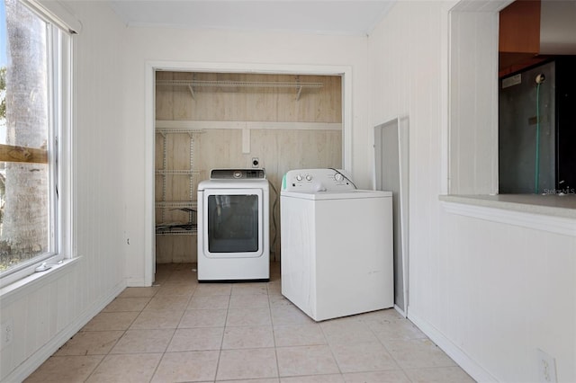 clothes washing area featuring light tile patterned floors, laundry area, crown molding, and washer and dryer