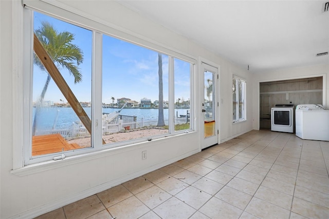 unfurnished sunroom featuring a water view, visible vents, and washer and dryer