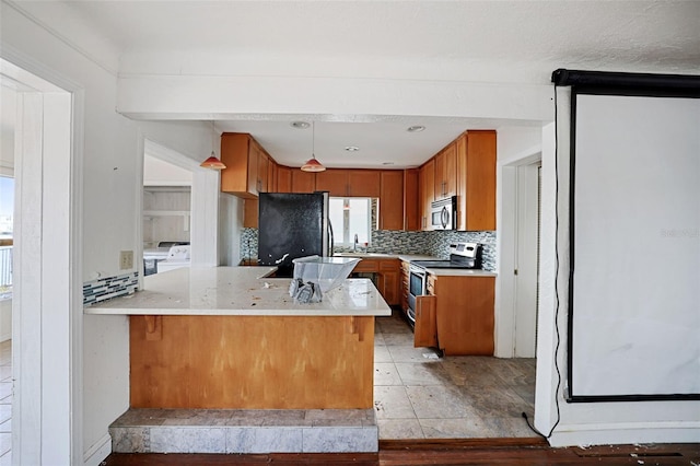 kitchen with a peninsula, stainless steel appliances, light countertops, and washer and dryer