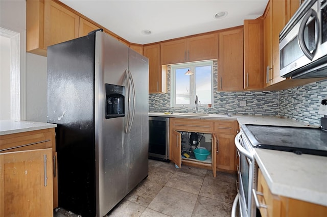 kitchen featuring light countertops, decorative backsplash, appliances with stainless steel finishes, brown cabinetry, and a sink