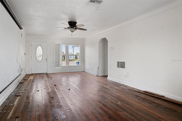 unfurnished living room featuring arched walkways, ceiling fan, dark wood-style floors, and visible vents