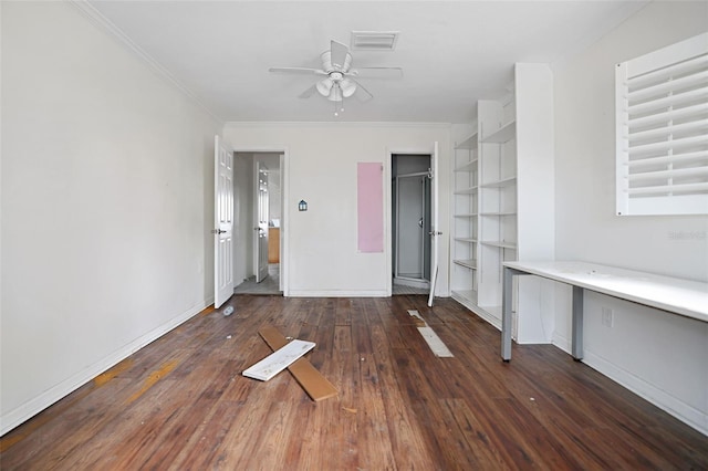 unfurnished bedroom featuring crown molding, built in desk, visible vents, dark wood-type flooring, and baseboards