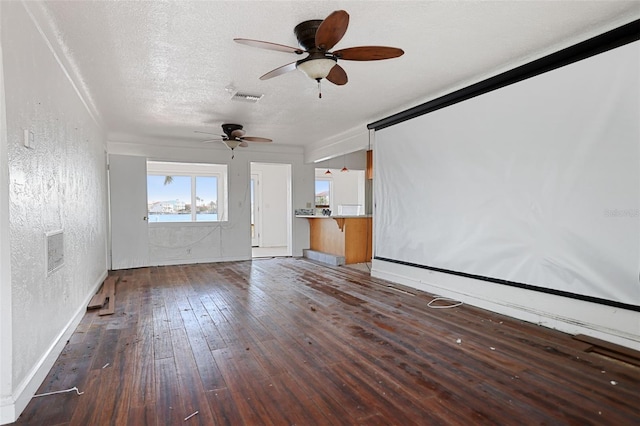 unfurnished living room with dark wood-style floors, a textured wall, a textured ceiling, and visible vents