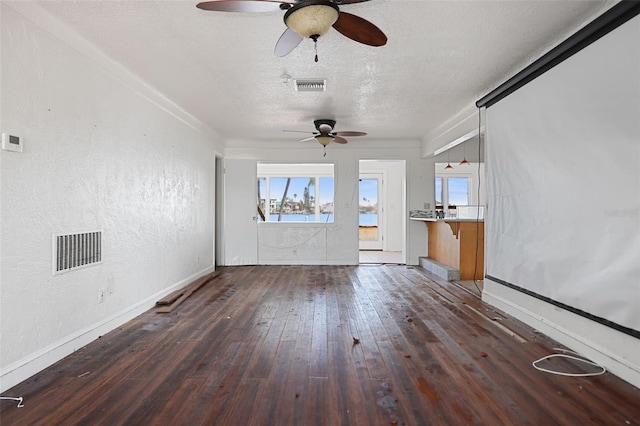 unfurnished living room featuring a textured ceiling, visible vents, dark wood-style flooring, and a textured wall