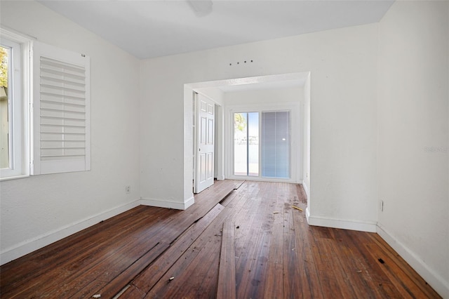 spare room featuring dark wood-style floors, plenty of natural light, and baseboards