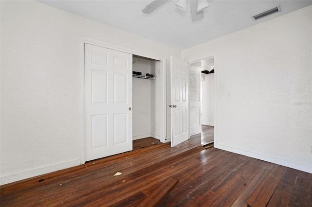 unfurnished bedroom with dark wood-style floors, baseboards, visible vents, and a closet