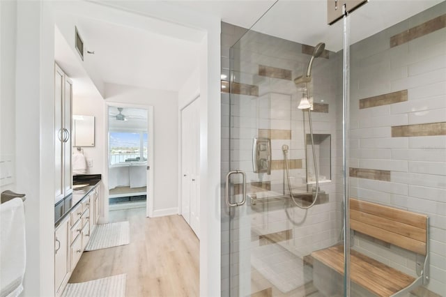 bathroom featuring hardwood / wood-style flooring, vanity, a shower with door, and ceiling fan