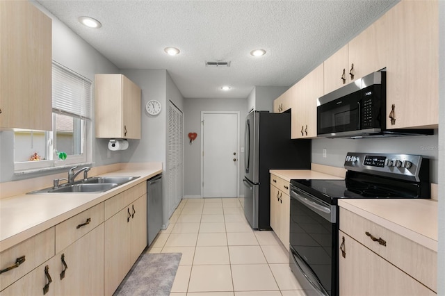 kitchen with light tile patterned flooring, appliances with stainless steel finishes, sink, and light brown cabinetry