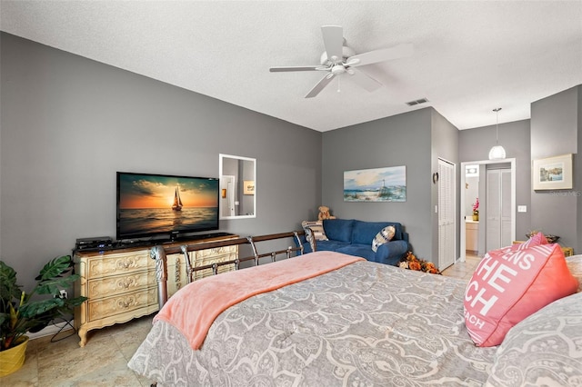 bedroom with ceiling fan, ensuite bathroom, and a textured ceiling