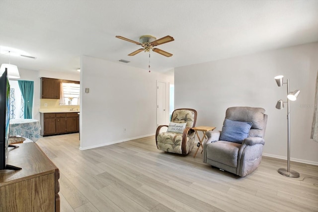 sitting room with ceiling fan and light wood-type flooring