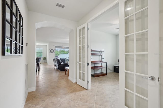 7580 Pool Compass Loop, Wesley Chapel, FL 33545 - hallway with french doors, visible vents, arched walkways, baseboards, and light tile patterned flooring